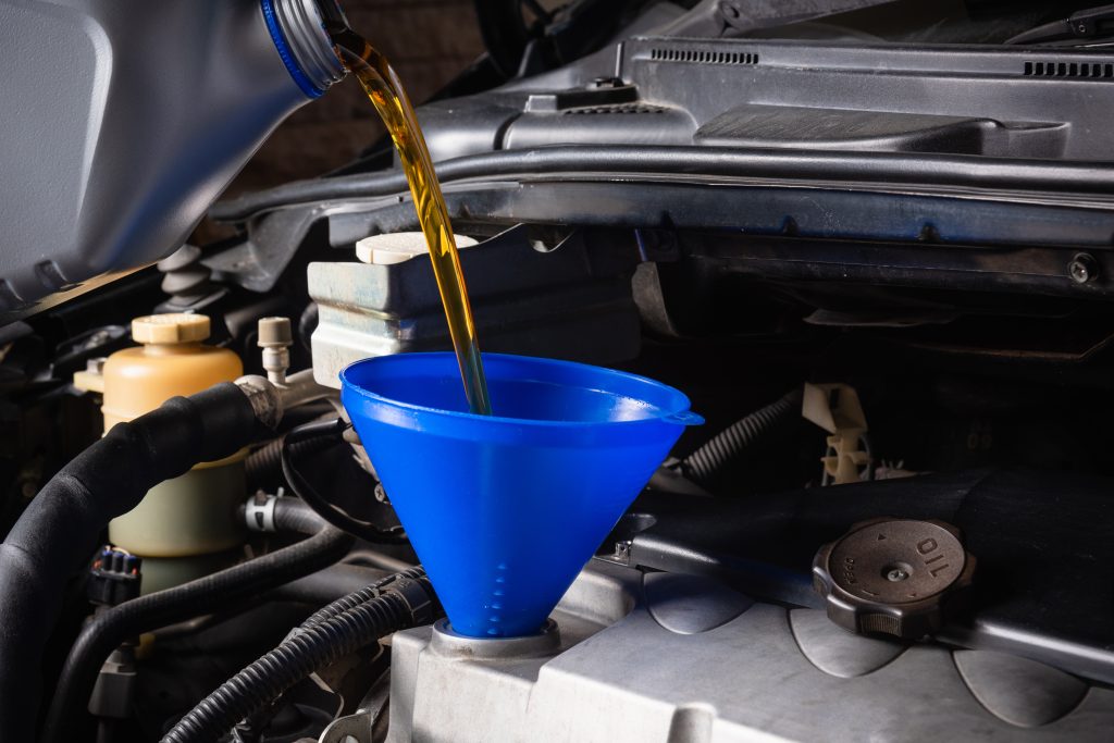 mechanic service repair car refueling pouring from bottle change lubricant oil